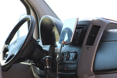 Inside an RV rental: Dashboard view with Mercedes steering wheel, manual shifter, and tablet for easy navigation.