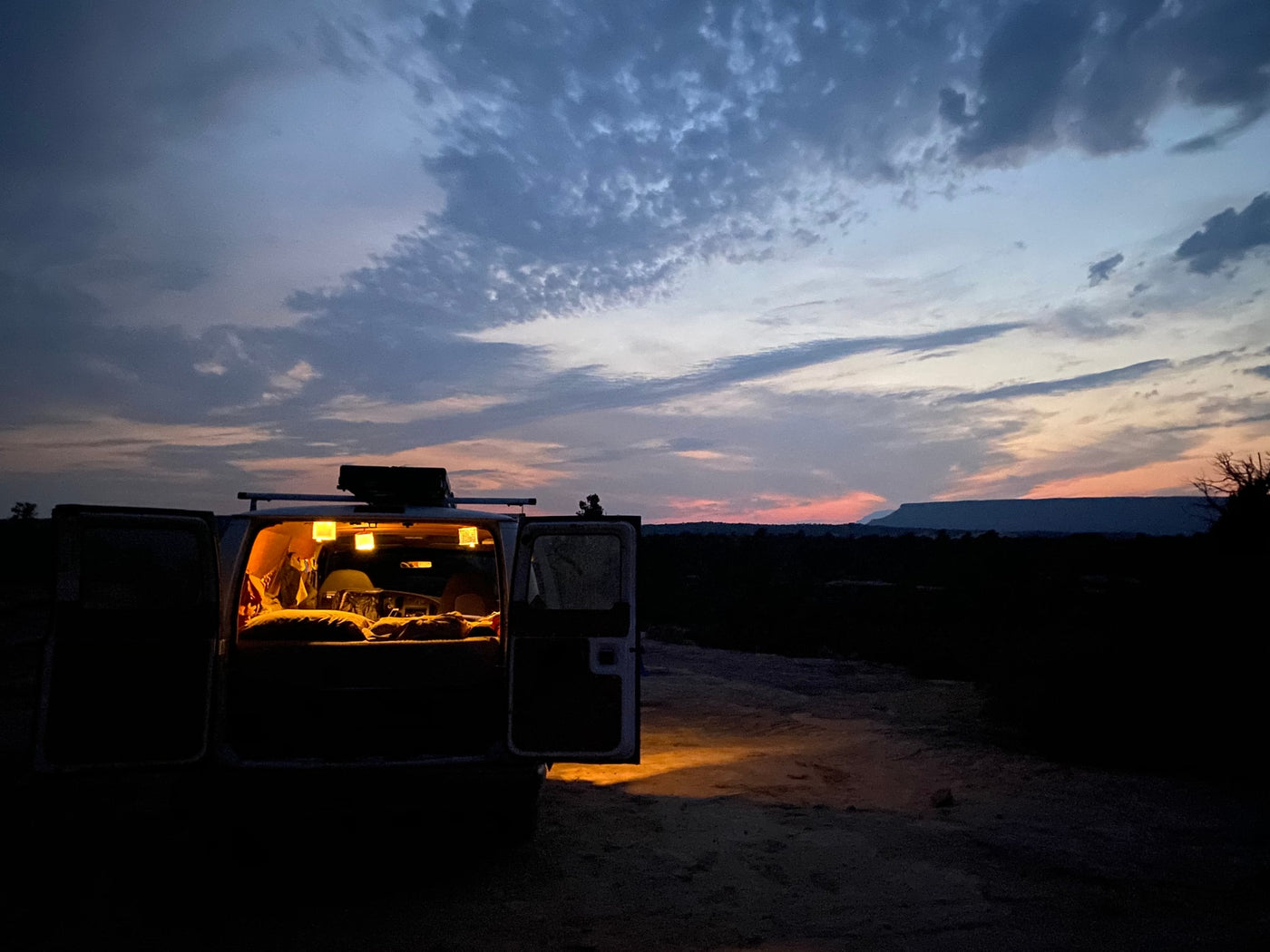 RV rental parked at dusk with illuminated interior and open doors, offering a view of a flat-topped mountain under a colorful sky. — photo 14