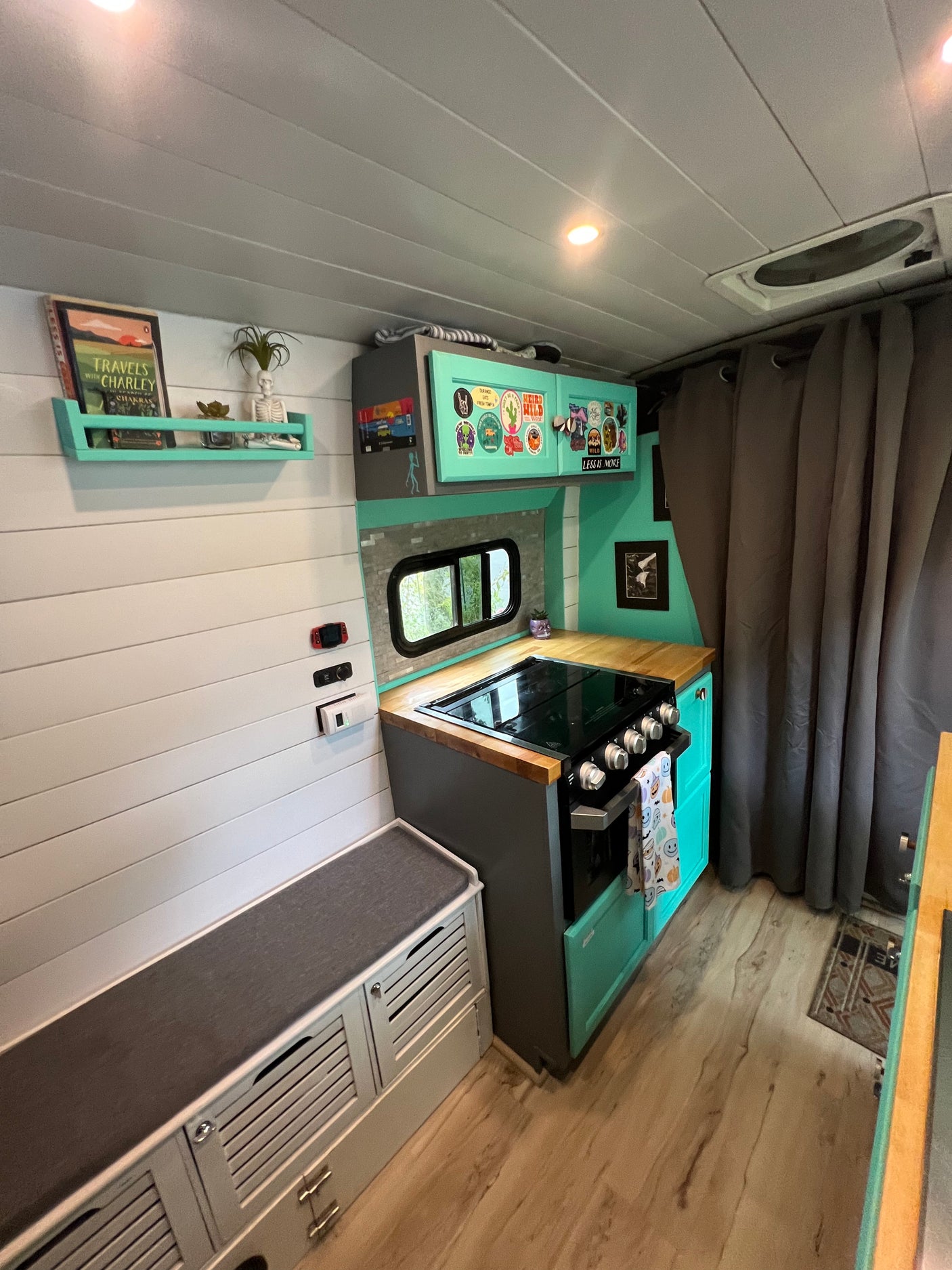 Explore this vibrant RV rental's mobile kitchen! Features mint green cabinets, wood counters, stove, and a cozy bench area.