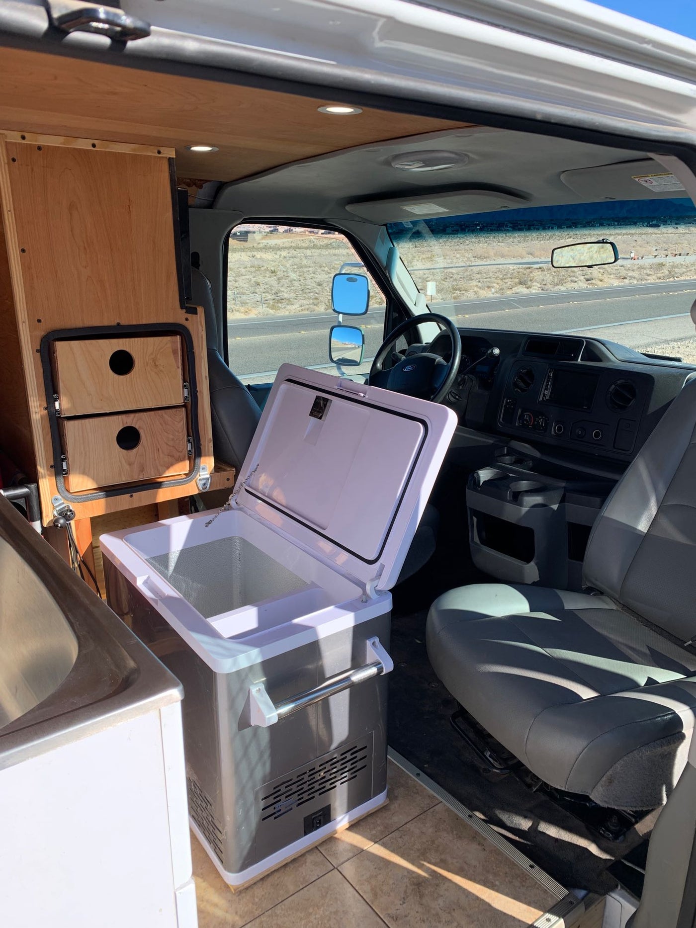  and wooden interior. Driver's seat visible.|RV rental van interior with an open portable fridge — photo 6