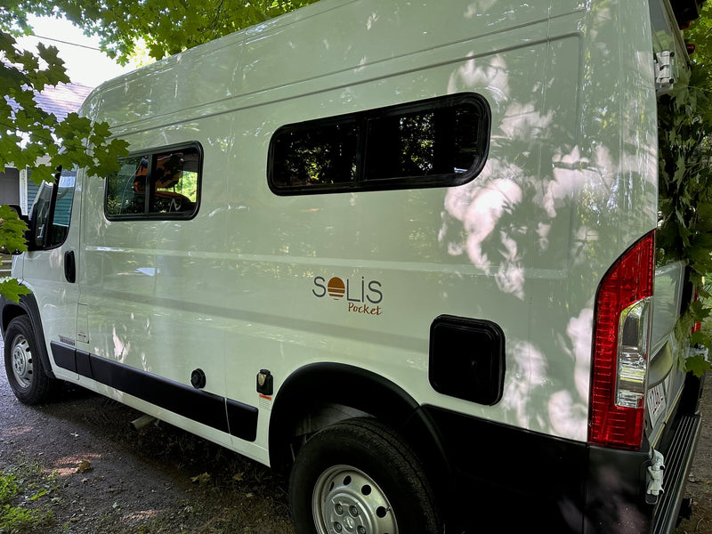  and a large window looking out to nature.|White Solis Pocket camper van RV rental with extended yellow awning on gravel. Perfect for outdoor adventures.|A white Winnebago camper van — photo 20