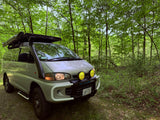 Adventure-ready Mitsubishi Delica van with snorkel, bull bar, awning. Perfect RV rental for forest overlanding.