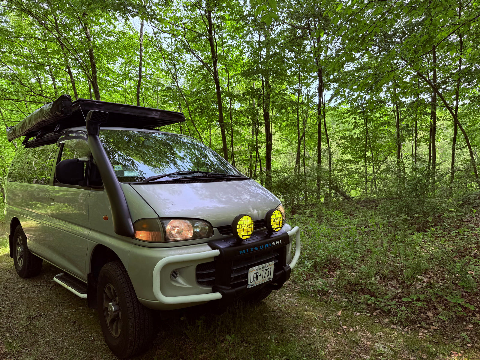 Adventure-ready Mitsubishi Delica van with snorkel, bull bar, awning. Perfect RV rental for forest overlanding.