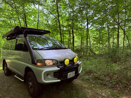 Adventure-ready Mitsubishi Delica van with snorkel, bull bar, awning. Perfect RV rental for forest overlanding.