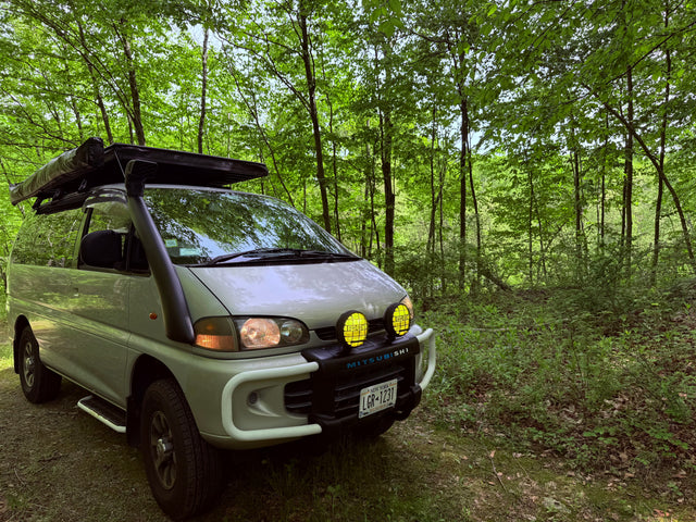 Adventure-ready Mitsubishi Delica van with snorkel, bull bar, awning. Perfect RV rental for forest overlanding.