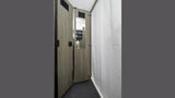 View inside an **RV rental** bathroom: features wood-look door with mirror, and white shower curtain for a compact **shower** area.