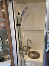 Compact RV rental interior: a space-saving bathroom with handheld shower and two sinks.
