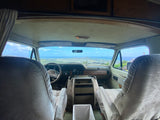 Inside an RV rental showing the front seats, dashboard, and a stunning panoramic view of a Hawaiian city, ocean, and Diamond Head.