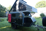 This rugged off-road camping trailer with a pop-up tent, ready for your next RV rental adventure, features mounted traction boards & shovels.