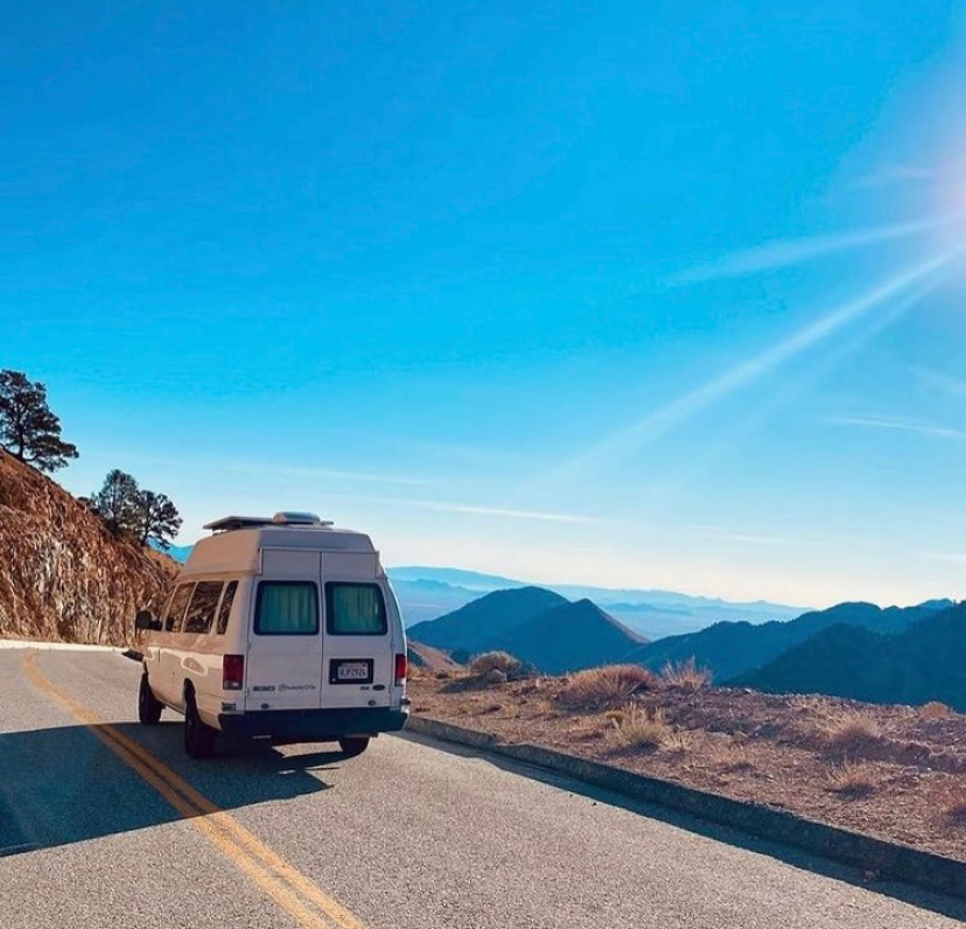 Epic rv rental journey: White camper van overlooks stunning mountain vista from a winding road under a bright blue sky. — photo 19