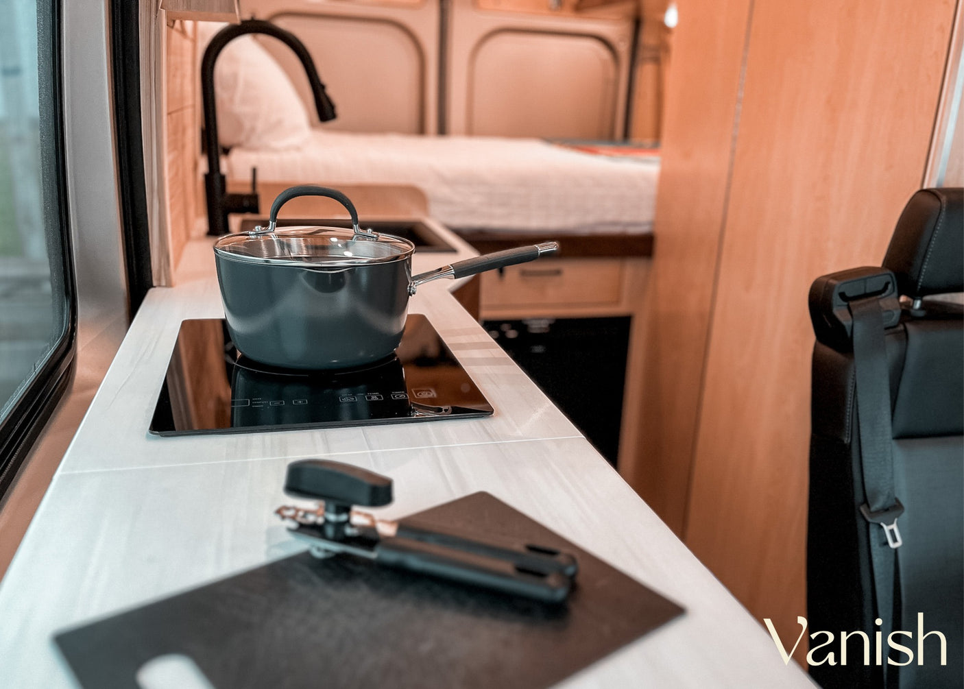 Inside your RV rental: Enjoy a well-equipped mobile kitchen with induction cooking & cozy bed. Perfect for van life.