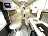 Modern RV rental interior showing a comfortable living space with facing sofas and a compact kitchen.