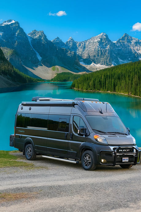 Dark grey RV rental camper van parked by a vibrant turquoise lake, towering mountains, and lush pine forests.