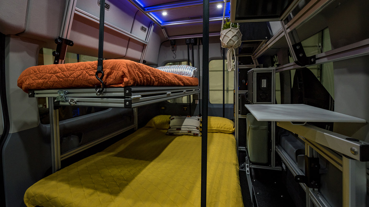 This RV rental shows a clever camper van interior with modular bunk beds, featuring orange and yellow bedding for compact travel.