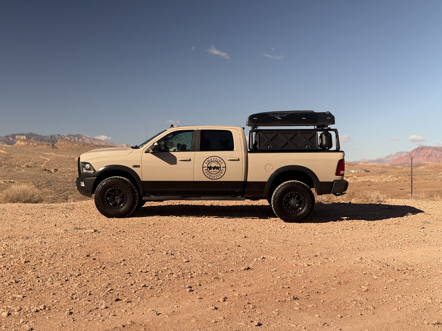 Equipped tan truck with rooftop tent parked in arid mountains; a versatile RV rental for desert adventures.