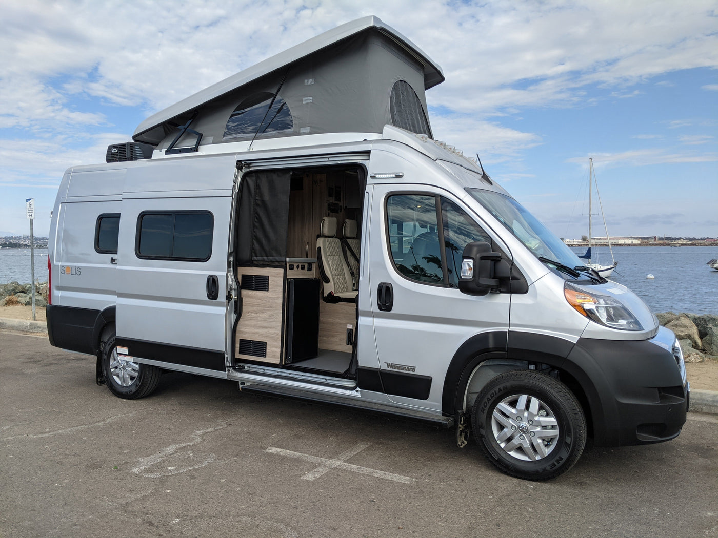 Silver Winnebago Solis camper van with pop-top extended. Interior visible, ready for your RV rental adventure.