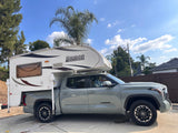 A gray Toyota Tundra pickup truck with a white Lance truck camper mounted on its bed, ready for your RV rental adventure.