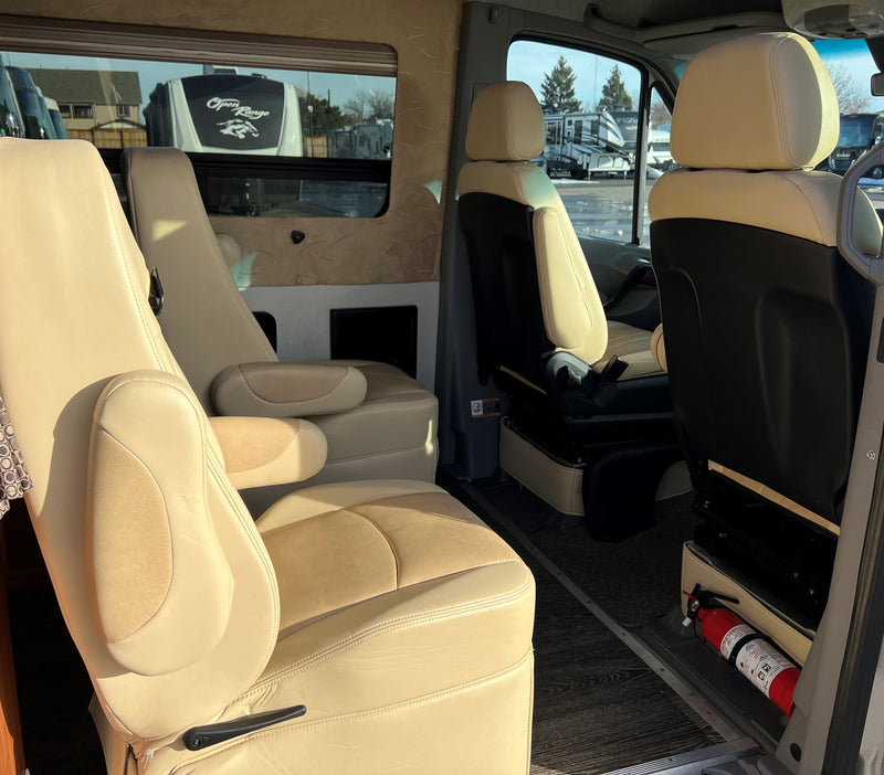 Spacious RV rental interior featuring tan leather captain's chairs and wood-look flooring. Fire extinguisher visible. — photo 6