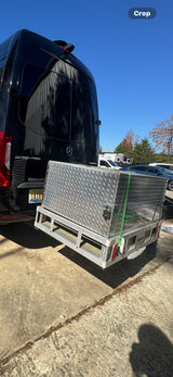 Black Mercedes Sprinter RV rental with a large, secure diamond plate cargo box on a hitch carrier for extra storage.