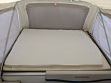 RV rental pop-up camper's interior bed: layered mattresses with an "EXIT" sign above. Quicksilver branding visible.