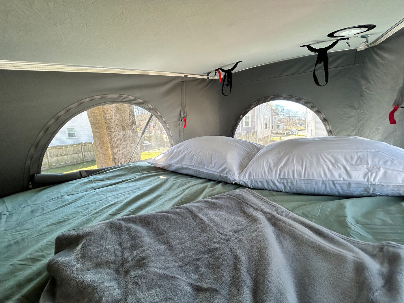  and unique round tent windows.|Pop-top RV rental van in a snowy parking lot with other cars and a child. Ready for winter travel adventures!|This dark Winnebago Solis camper van rv rental is parked oceanside on a cloudy day — photo 3