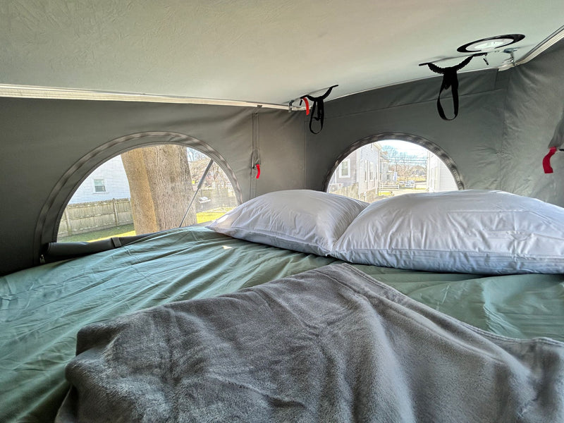  and unique round tent windows.|Pop-top RV rental van in a snowy parking lot with other cars and a child. Ready for winter travel adventures!|This dark Winnebago Solis camper van rv rental is parked oceanside on a cloudy day — photo 3
