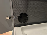 RV rental interior: Grey door with hinge, dark grey textured wall, black access hatch, and white sink below.