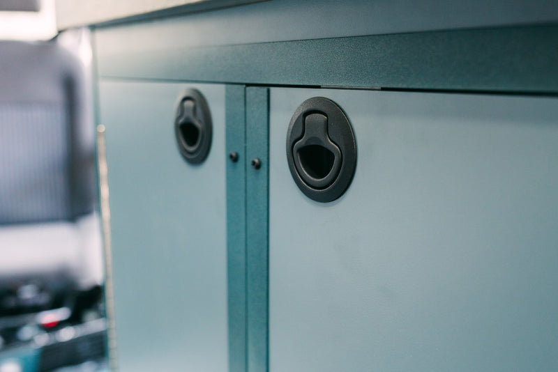 Light blue-gray cabinets with black flush latches provide secure storage in this RV rental's interior. — photo 6