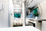 Cozy RV rental interior: modern kitchen, comfy bed, and nature views from the window, ideal for travel.