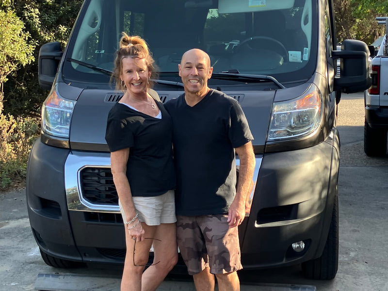  and a stunning mountain view.|View into an rv rental: a bed above under-bed storage holding a portable power unit (Hensel Off) and a Thetford Porta Potti.|Interior of an RV rental camper van looking forward. Dashboard — photo 18