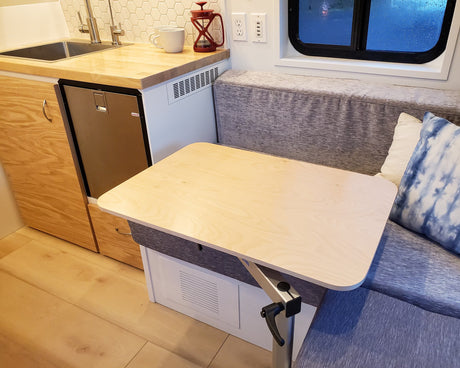 RV rental interior features a compact kitchenette with sink & fridge, a wooden dinette table, and cozy bench seating.