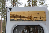 Custom wood art featuring a mountain, river, and bison scene adorns this RV rental's interior.