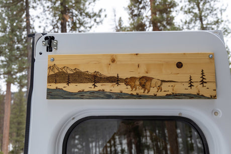 Custom wood art featuring a mountain, river, and bison scene adorns this RV rental's interior.