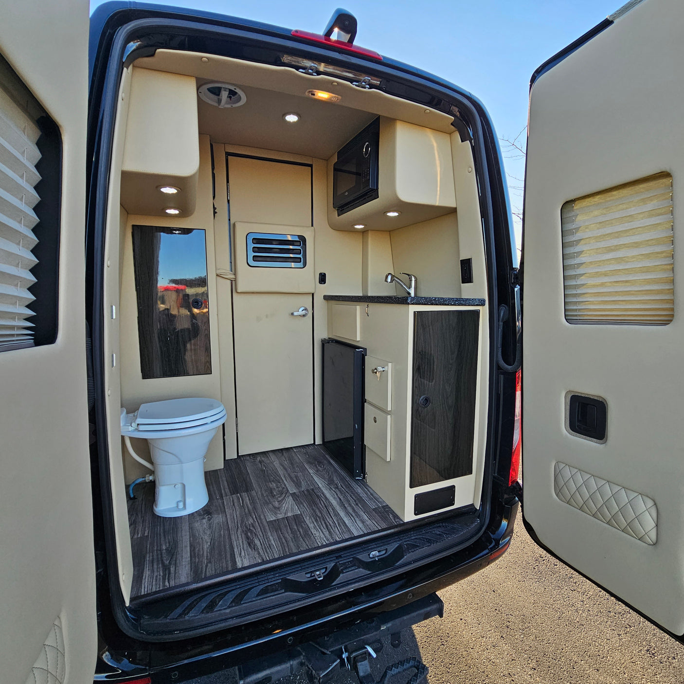 Explore this RV rental's compact camper van interior: kitchen with sink, microwave, fridge, and a toilet. Ideal for road trips.