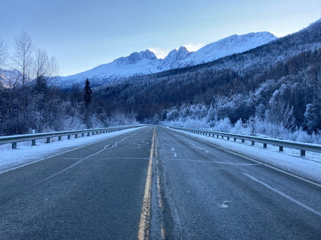 Endless snowy road leading to majestic mountains and frosty forests. Explore with an RV rental!