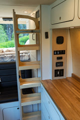 Interior of an **rv rental**, featuring a wooden bunk bed ladder, kitchen counter, and integrated control panel on the wall.