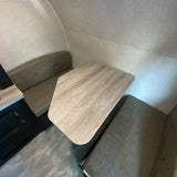 RV rental interior featuring a dinette with a light wood table, upholstered bench seats, and textured walls.