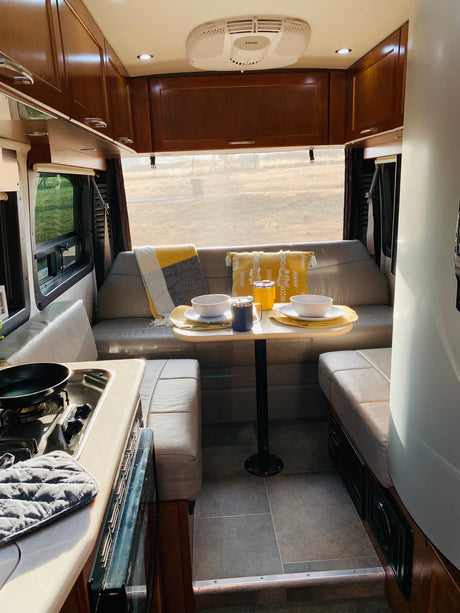 Cozy RV rental interior with dining area, kitchen, and comfy seating, ready for adventure.