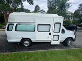 White Ford E-Series RV rental van, converted into a camper with high roof, side entry, and window blinds. Parked roadside.