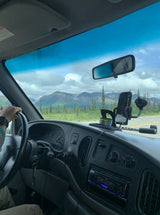 Scenic road trip from an RV rental: driver's dashboard with phone mount, expansive mountain & forest views.