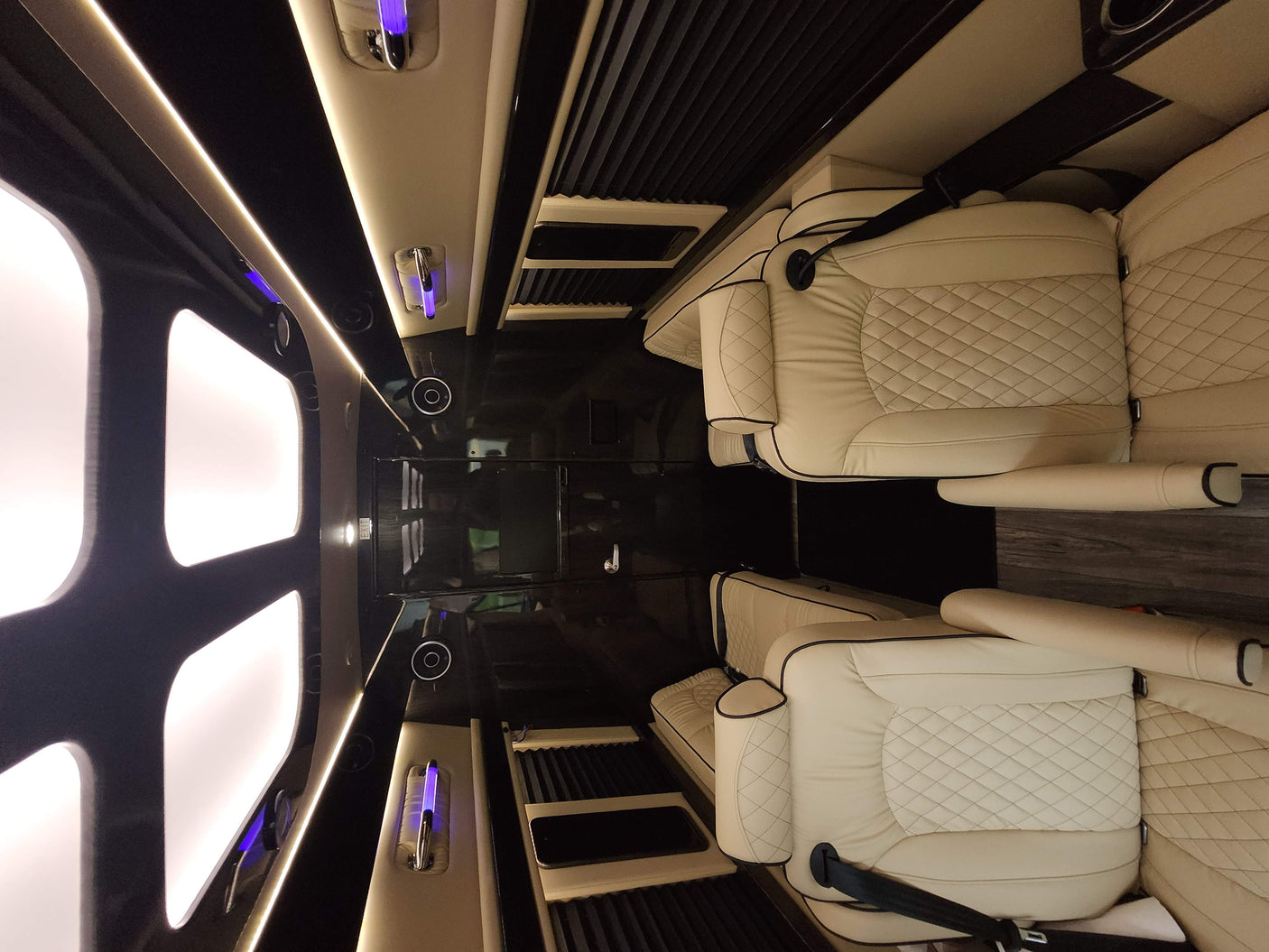 Spacious, luxurious RV rental interior featuring cream quilted leather seats, ambient lighting, and dark finishes.