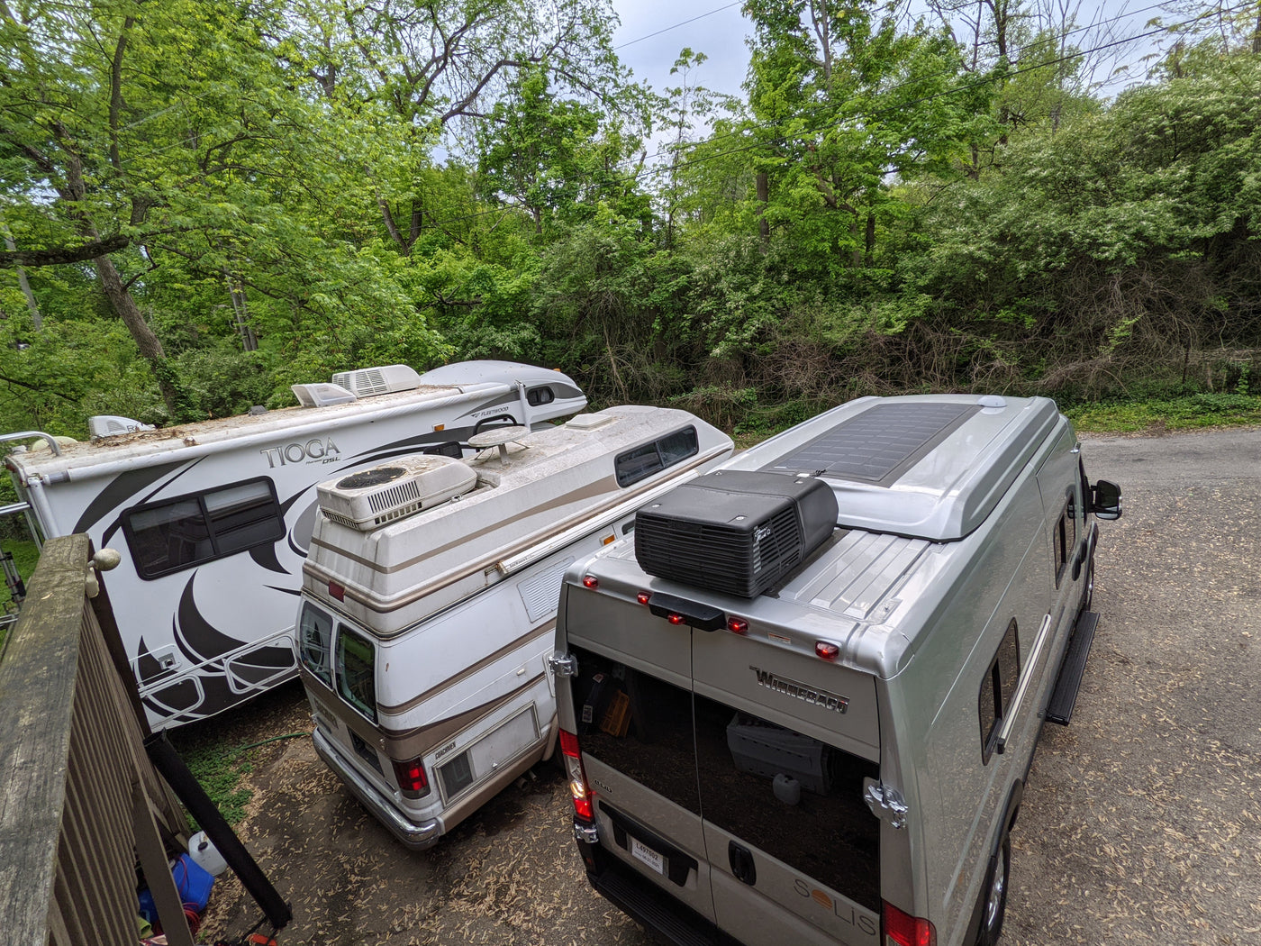 Overhead view of three parked RVs (Winnebago, Coachmen, Tioga) nestled among trees, perfect for rv rental adventures. — photo 18