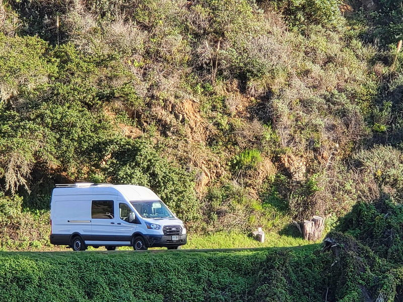 White RV rental van on a scenic road with vibrant green, sunlit hills. An ideal ride for travel and outdoor adventures. — photo 18