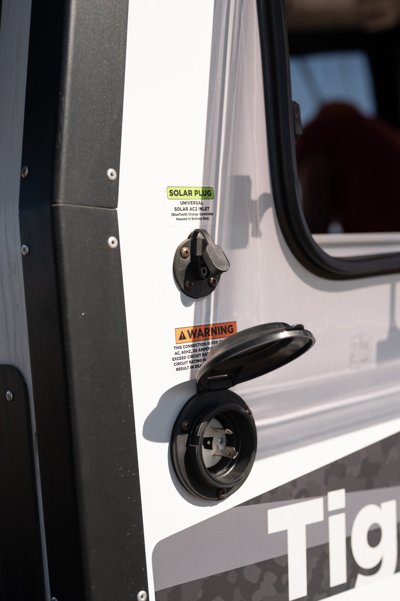This RV rental displays its specialized solar input and standard 30-amp shore power inlet for versatile energy options.
