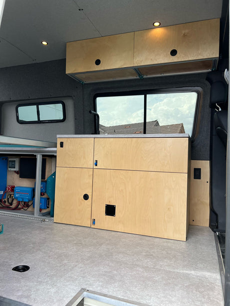 Inside this RV rental's custom camper van, light wood cabinetry, recessed lighting, and integrated power await your adventure.