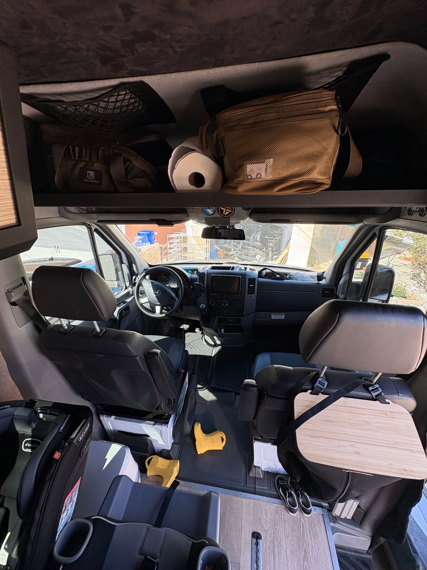 Inside an RV rental: a family-friendly camper van cockpit with overhead storage, child seats, and accessories ready for travel.