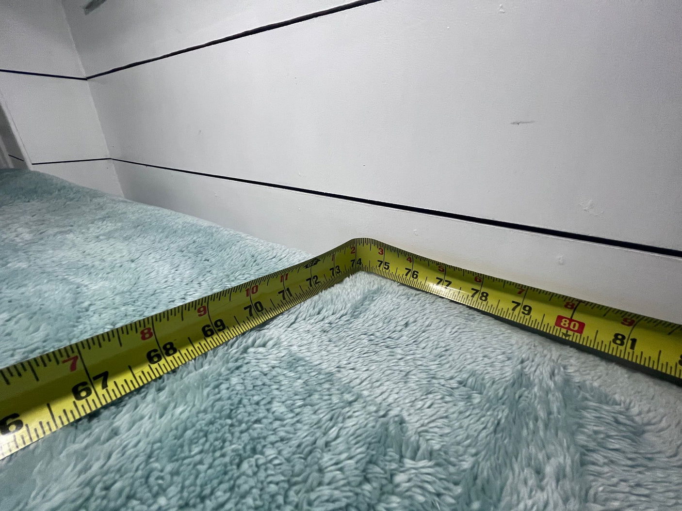 Yellow tape measure on a fuzzy blue blanket in an RV corner, showing 67-81 inches. Essential for rv rental space planning.