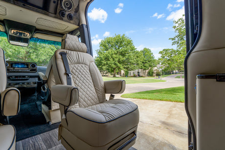 Luxury RV rental: Relax in a plush captain's chair with an open-door view of a serene suburban street.