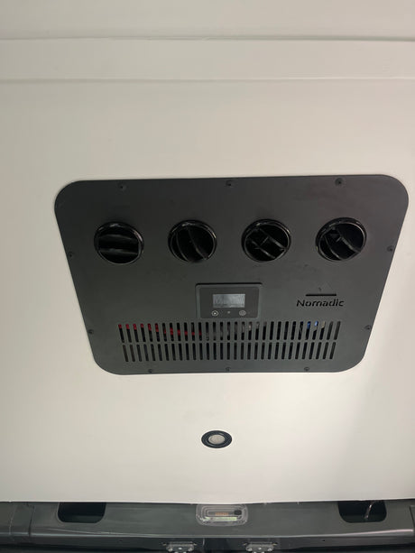 Overhead view of a Nomadic air conditioner with four adjustable vents and digital controls in an RV rental.