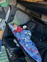 Child sleeping comfortably in a hanging bunk inside an RV rental, perfect for family van life adventures.